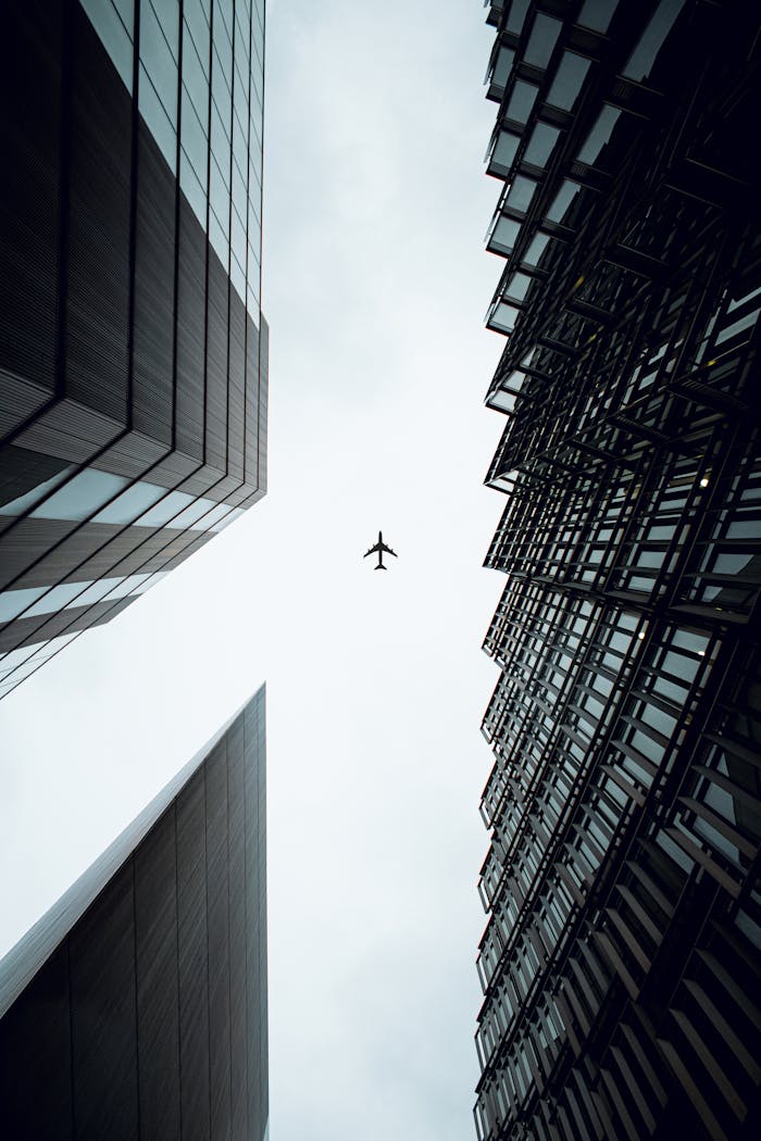 gallery-03 A dramatic view of an airplane flying above modern skyscrapers in London, UK.